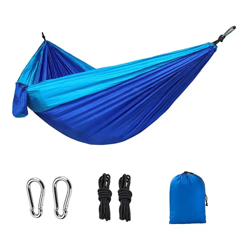 Blue parachute nylon outdoor camping hammock hung between two trees.