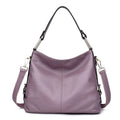 A vertical square-shaped genuine leather crossbody bag in black, showing external sewing lines and a crossbody strap.