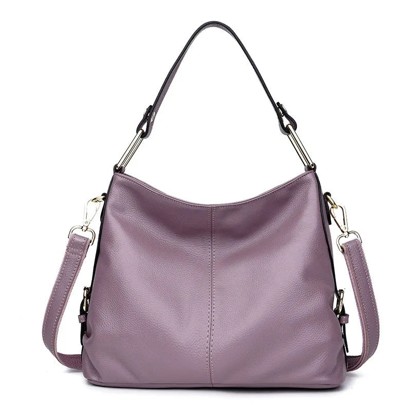A vertical square-shaped genuine leather crossbody bag in black, showing external sewing lines and a crossbody strap.
