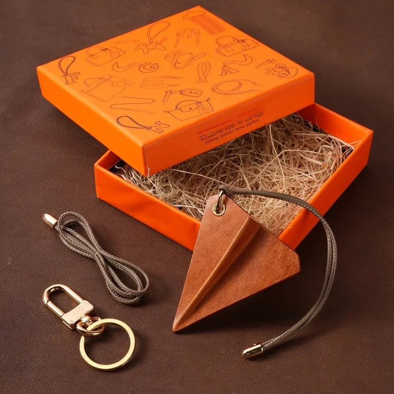 Crazy Crafts handmade cowhide paper airplane pendant in brown, on a bag