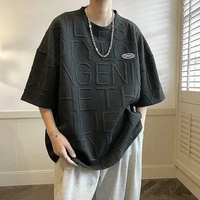 Grey men's loose t-shirt with a raised white 3D letter graphic on the chest.