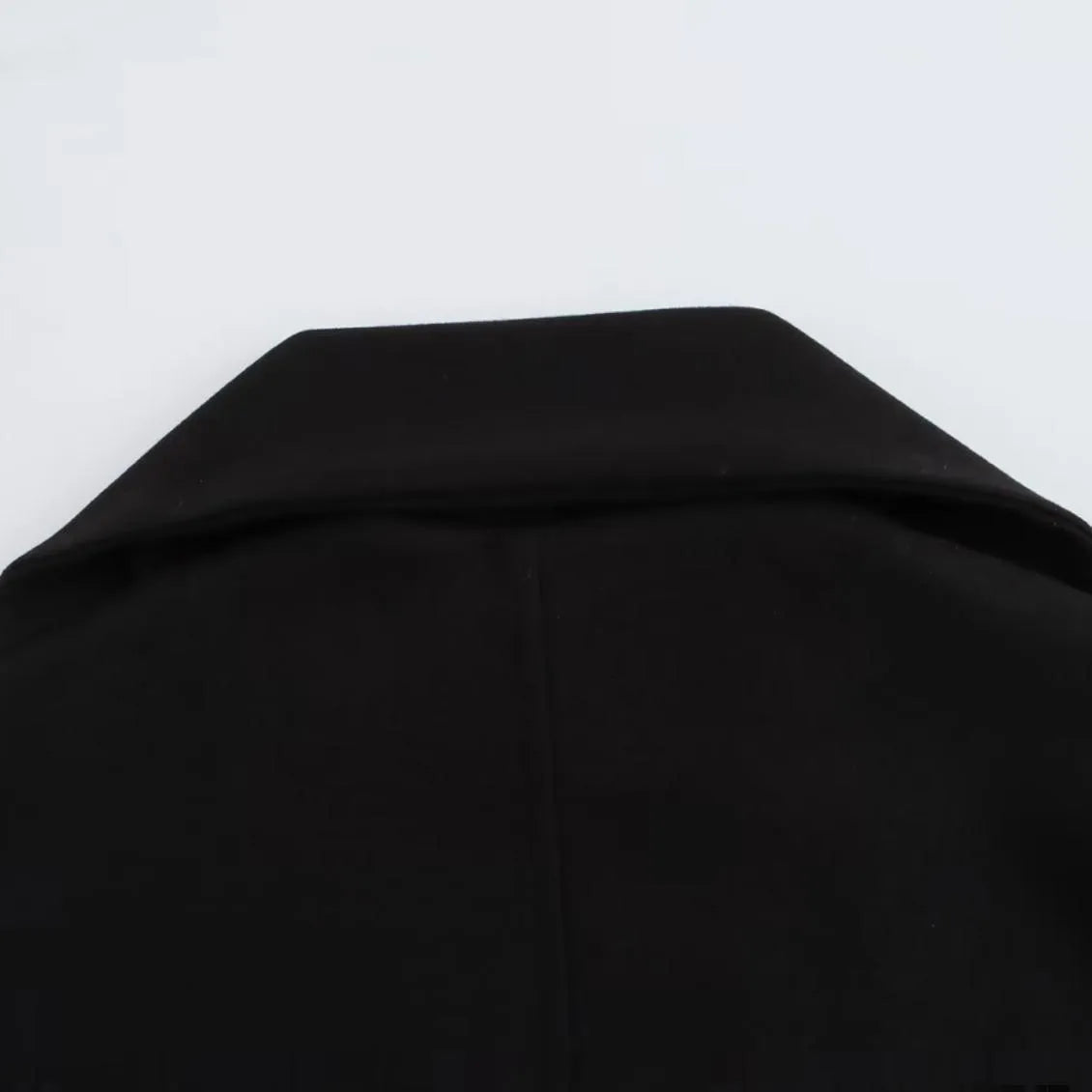 Women's long black overcoat with artificial fur collar, showing extended length and street fashion style.