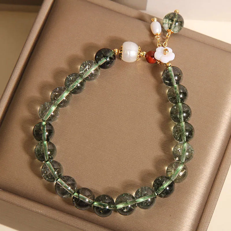 Green phantom quartz crystal bracelet with a silver shell flower charm on a model's wrist.