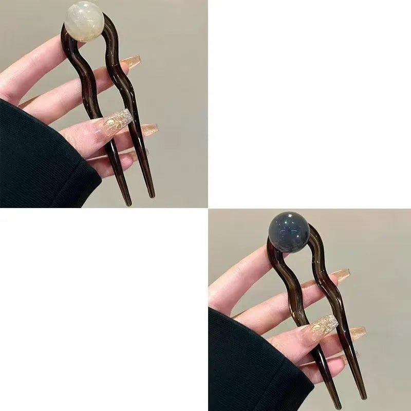 Acrylic U-shaped hair barrette with a small spherical decoration in a beige and caramel two-tone colour combination.