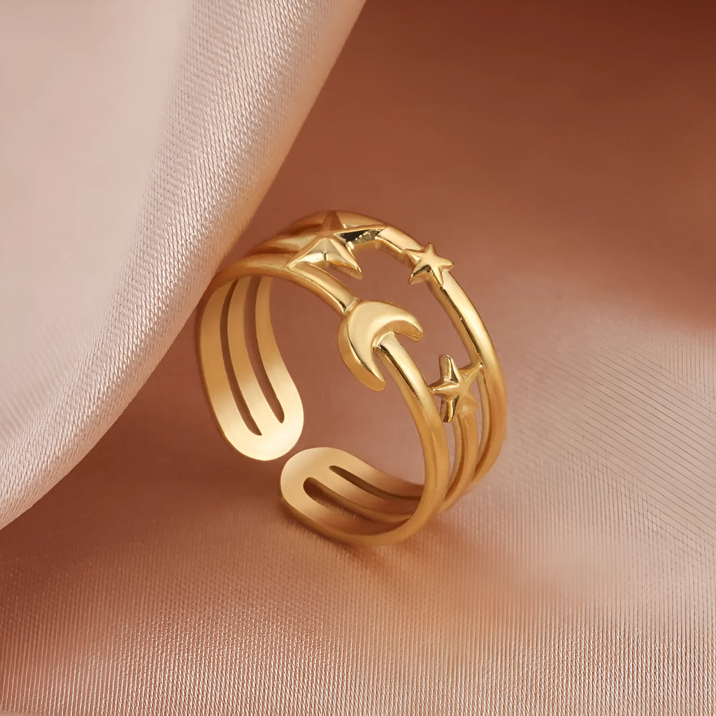 Gold electroplated stainless steel star shaped opening ring on a plain background