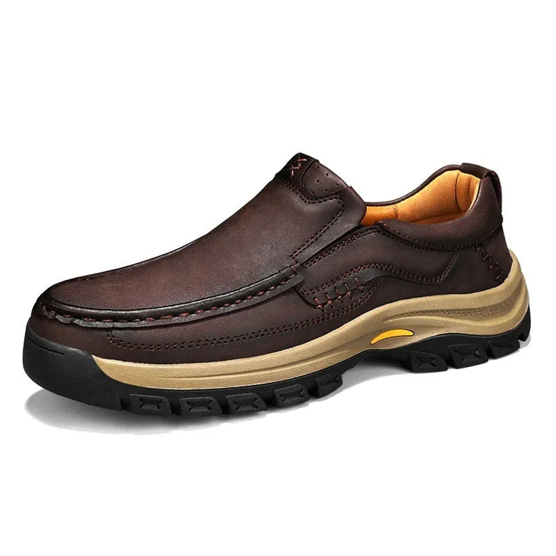 Men's black thick-soled mountaineering leather shoes with round toe and visible stitching on a natural background.