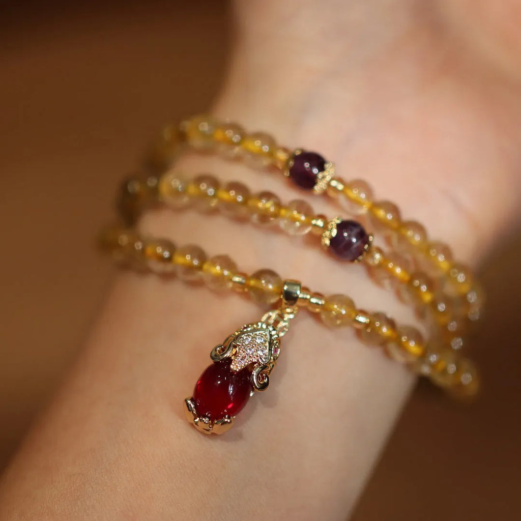 Gold rutilated quartz bracelet with three circles design and hanging chopsticks on wrist