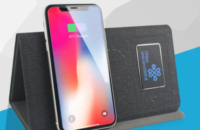 Folding cloth wireless charging mouse pad and small black wireless mouse shown with a portable handbag.