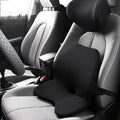 Black memory foam car lumbar support cushion with elastic straps, shown on a grey car seat.