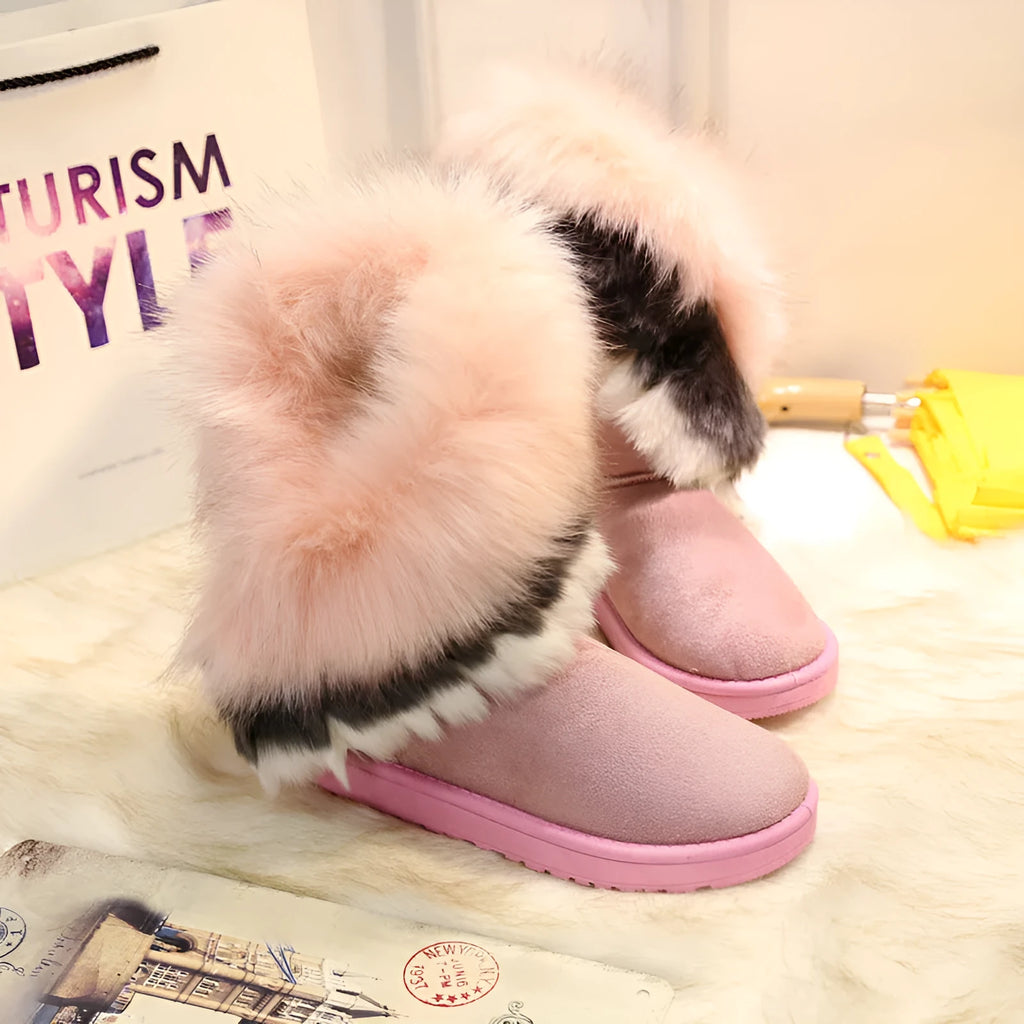 Women's winter snow boots in suede with fluffy fox fur trim and rubber sole on a snowy path