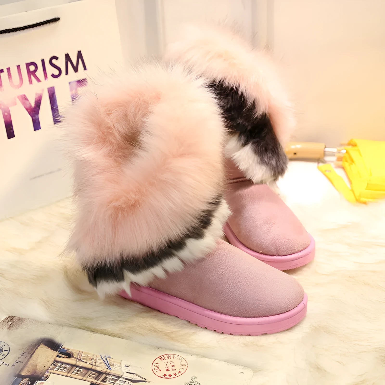 Women's winter snow boots in suede with fluffy fox fur trim and rubber sole on a snowy path