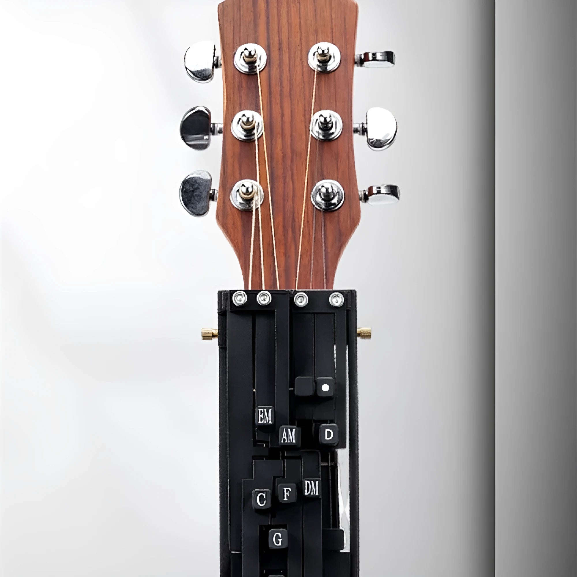 Black automatic guitar chord changing device for folk music beginners on a guitar neck.