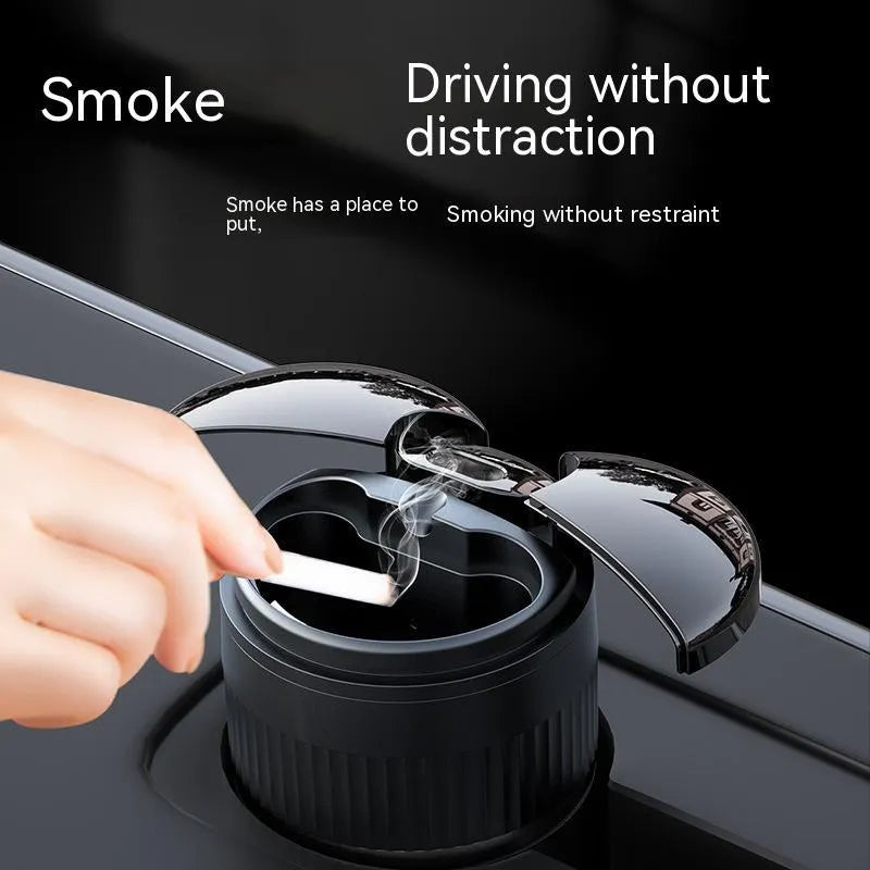 Smart black metal car ashtray with lid, showing compact size next to a charging cable.