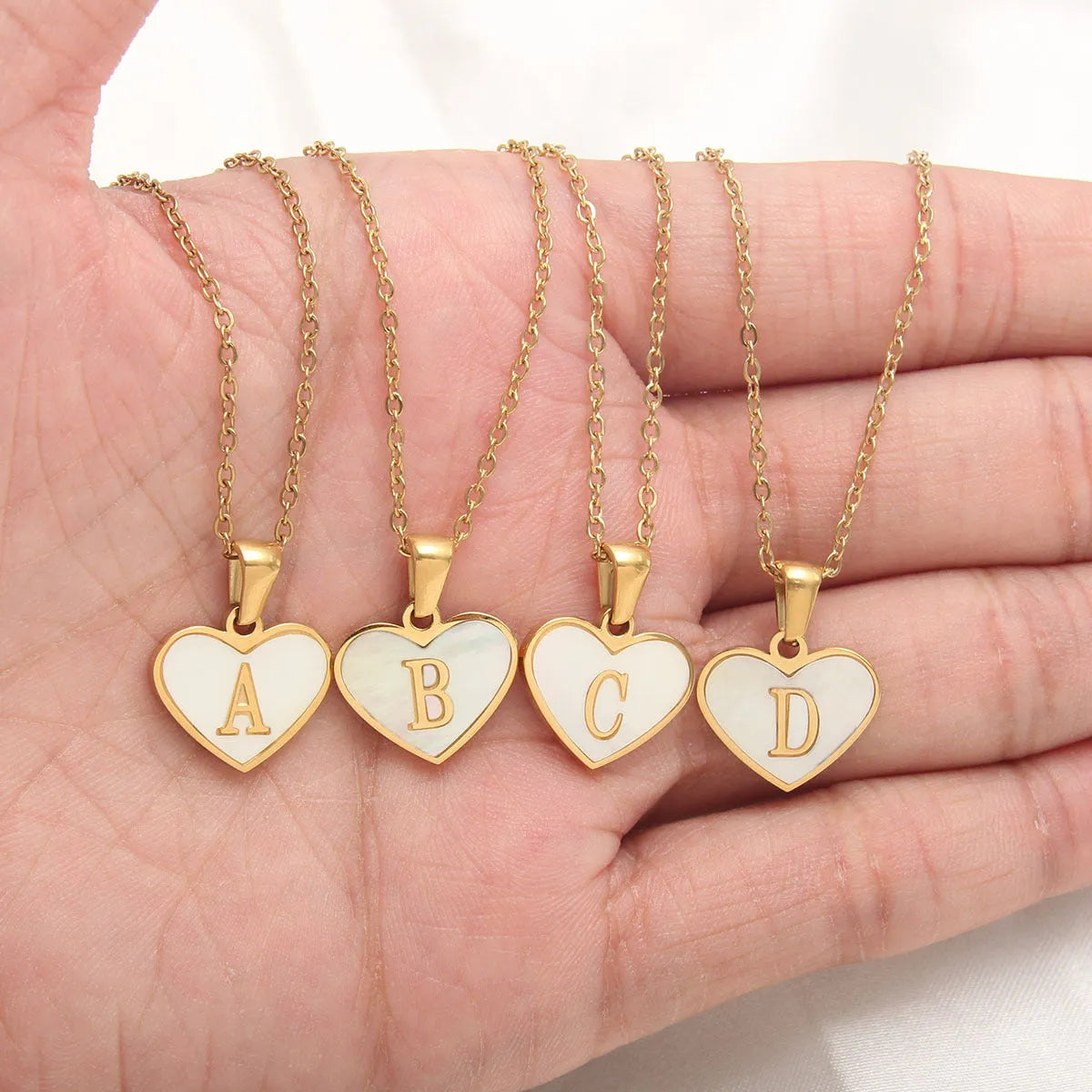 Gold-plated heart necklace with white shell pendant and initial personalisation on a stainless steel chain.