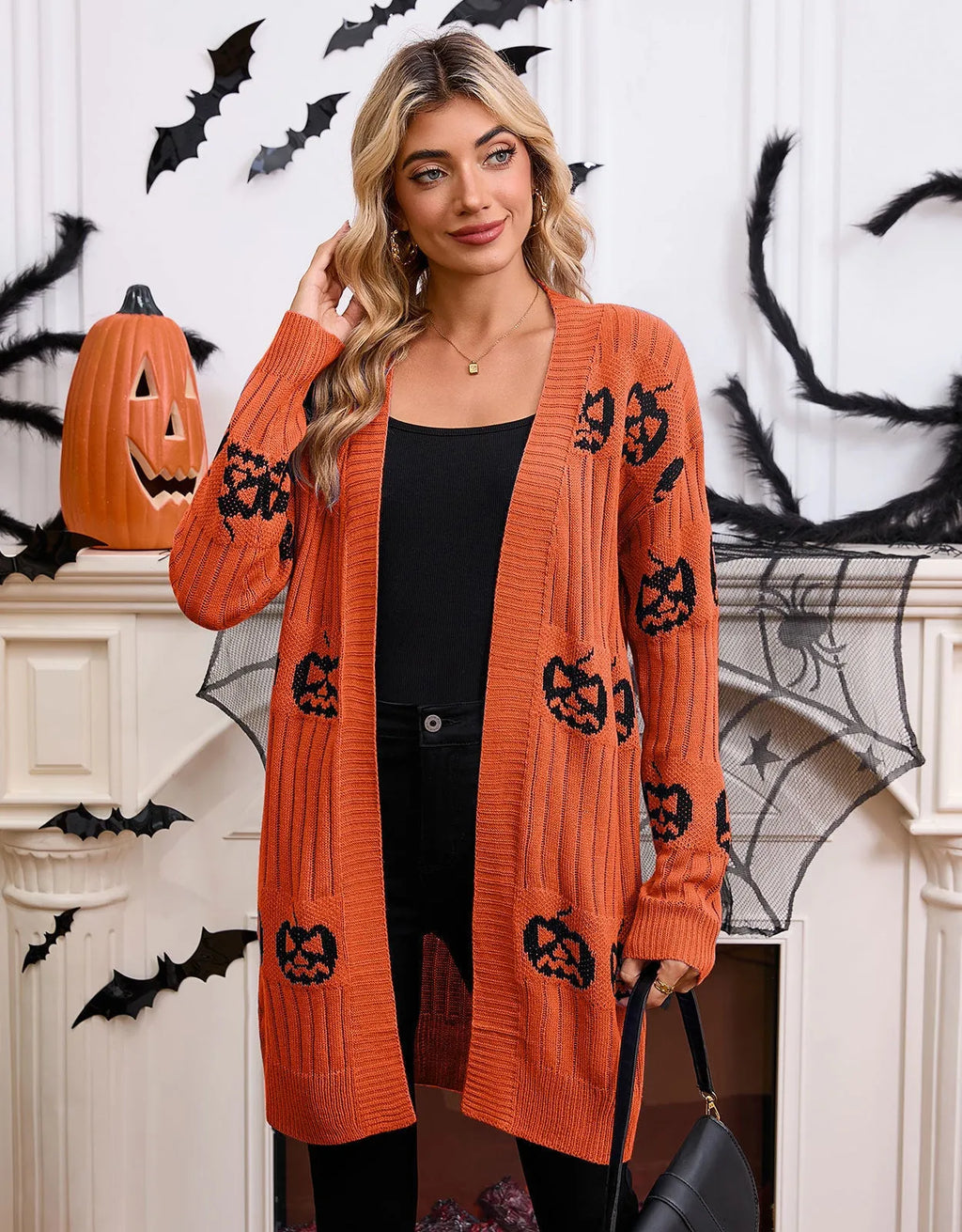 Women's black Halloween cardigan with orange Jacquard knitted pumpkin head pattern, shown on a hanger.