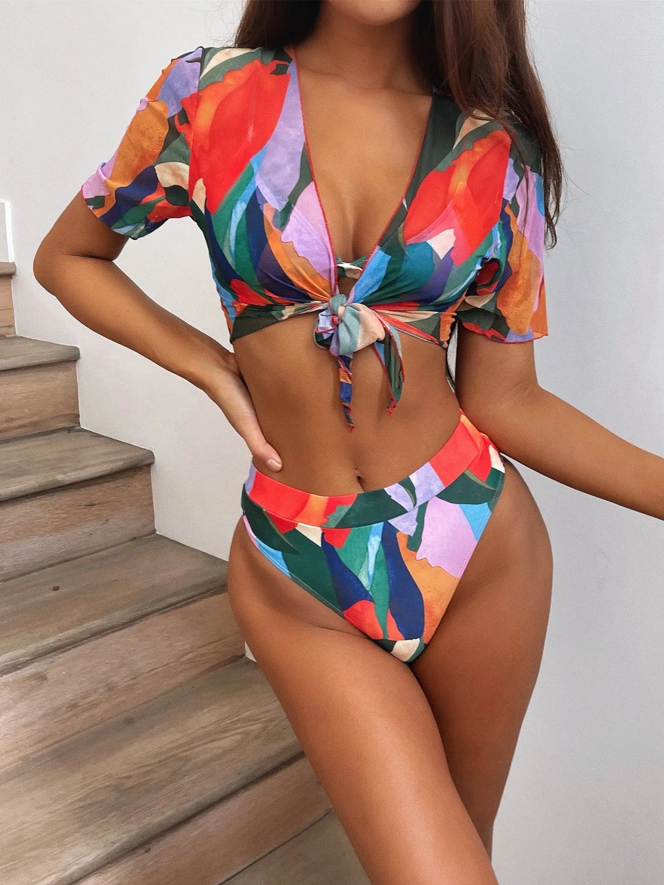 Red women's nylon split swimsuit on a hanger, showing printed design and bikini style.