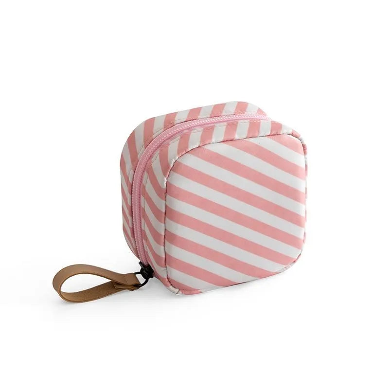 Blue cloth cube-shaped makeup bag with a zipper closure, resting on a surface.