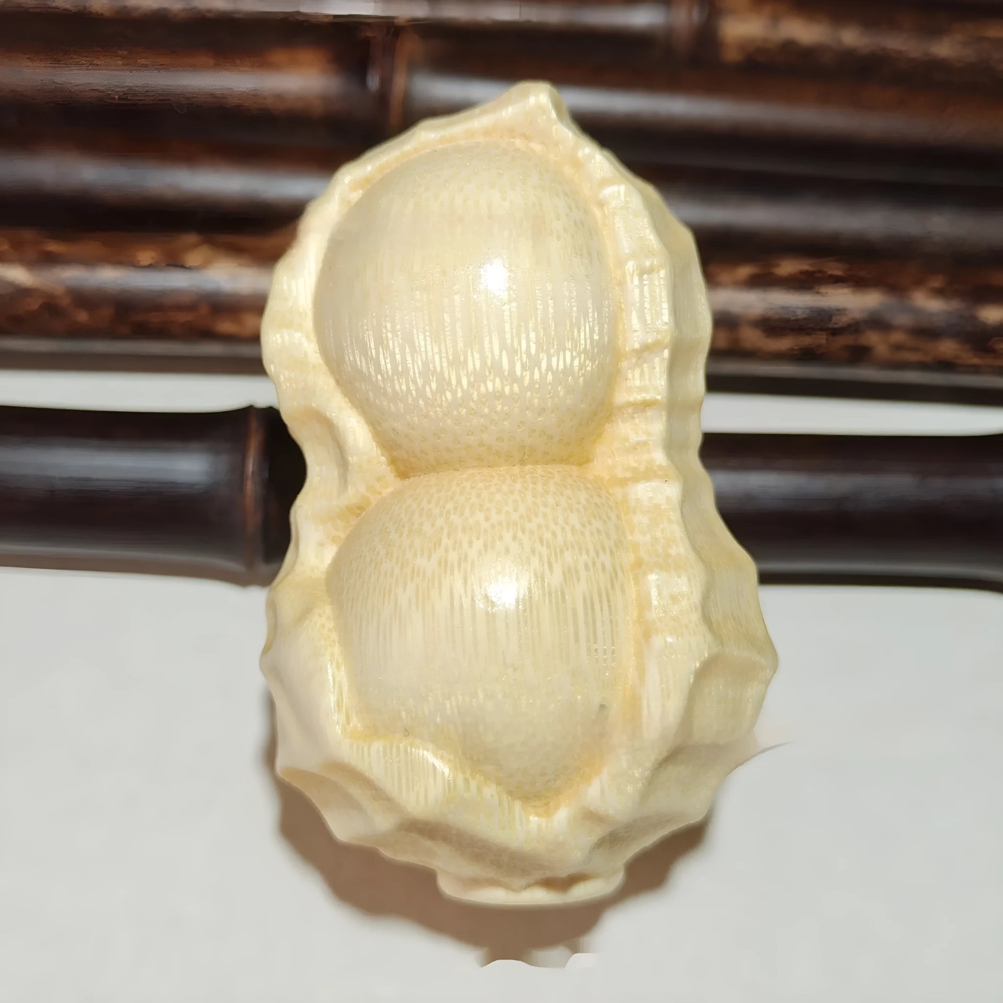 Modern minimalist solid bamboo carving peanut ornament on a neutral background.
