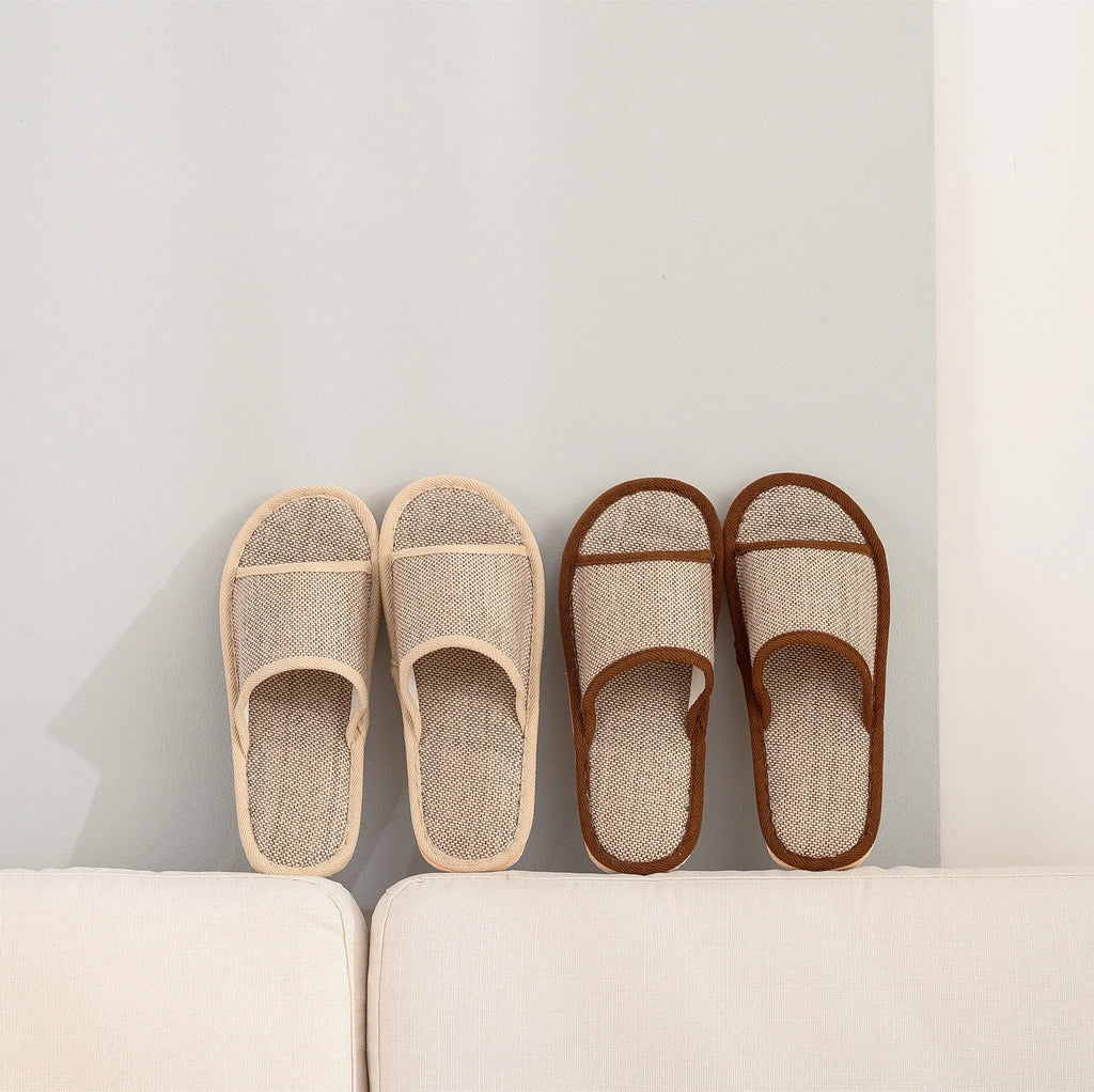 Women's open-toe linen slippers in light brown on a wooden floor, showing the breathable design and thickened sole.