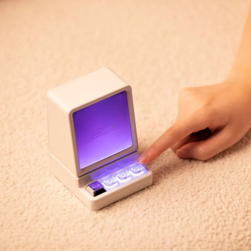 Light grey portable Bluetooth speaker shaped like a classic computer on a desk