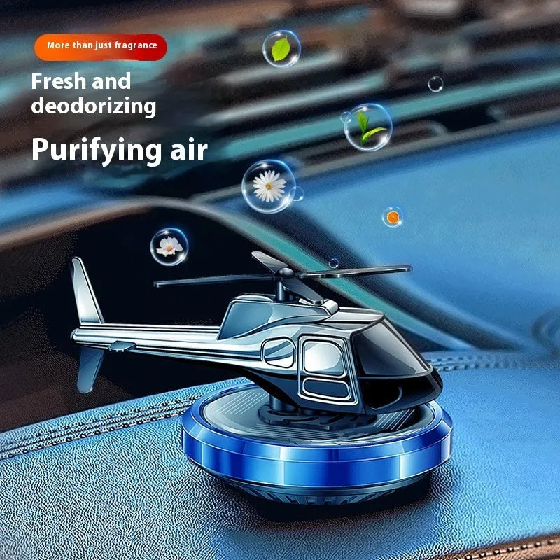 Silver metal solar-powered helicopter car ornament with rotating blades on a car dashboard.