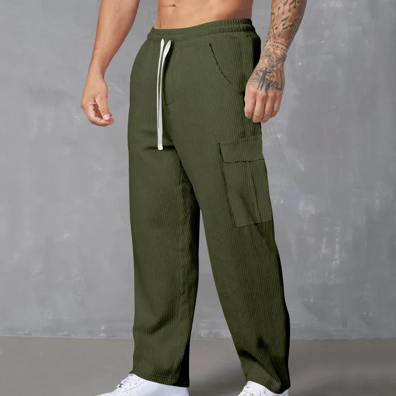 Man wearing loose-fitting straight-leg corduroy cargo trousers in navy blue with a drawstring waist.