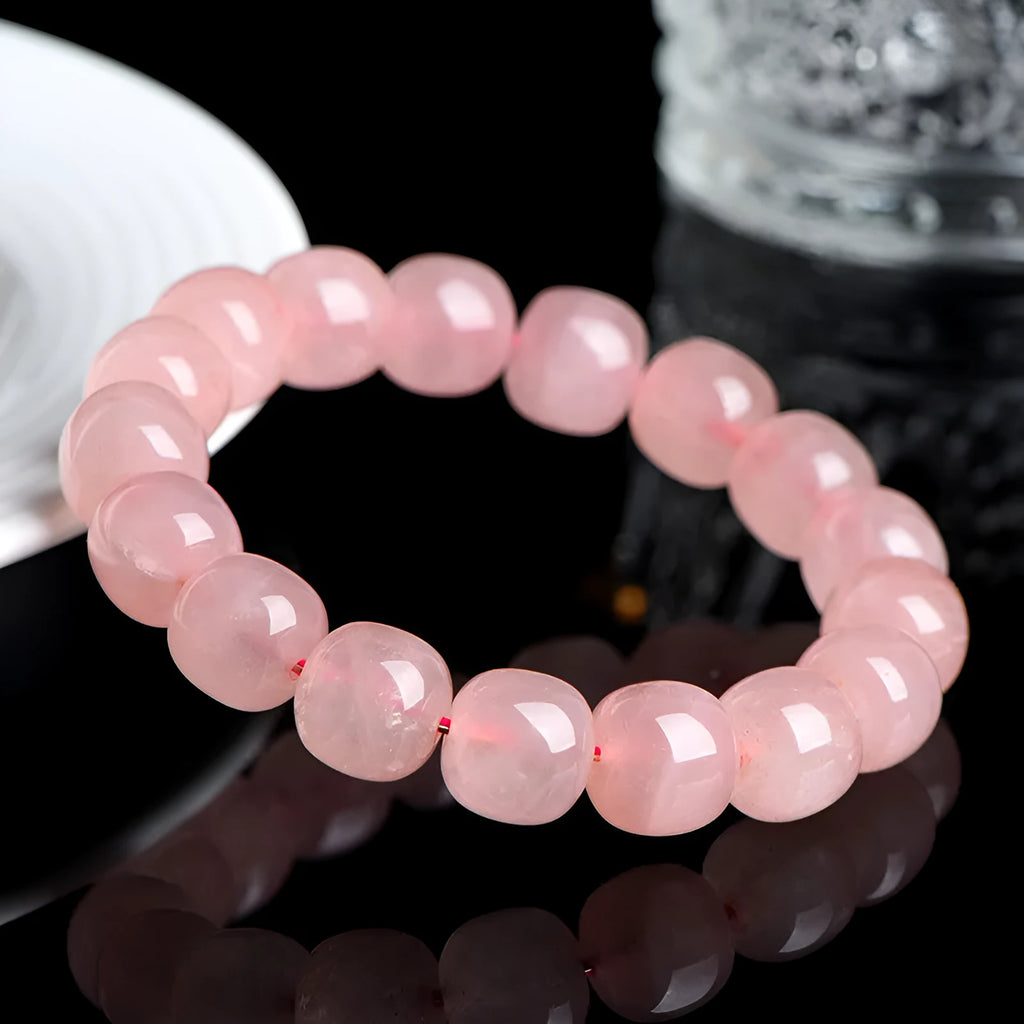 Pink crystal barrel-shaped bead bracelet on a wrist, showing geometric beads and polished finish.