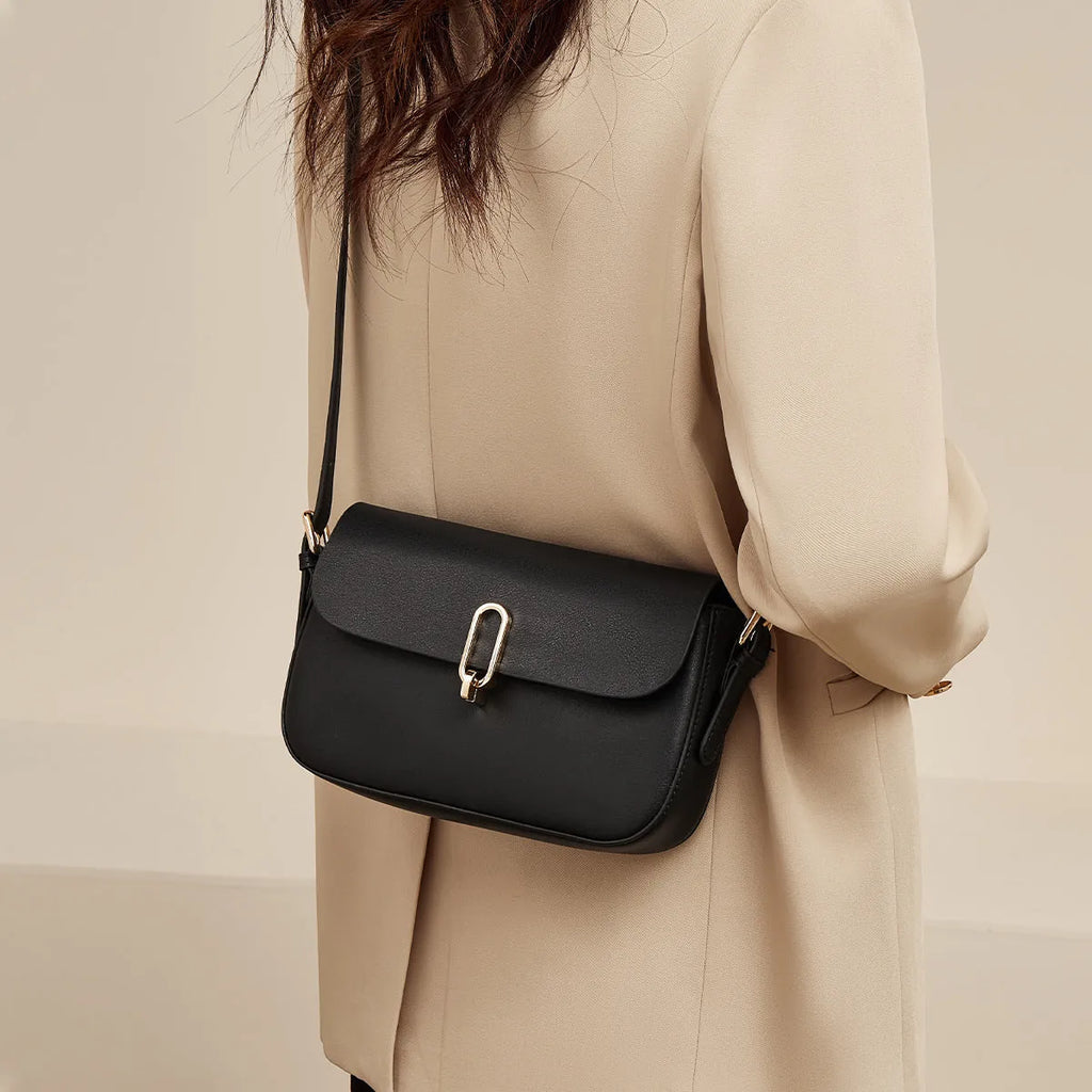 Black square leather messenger bag with shoulder strap showing lock closure and urban design