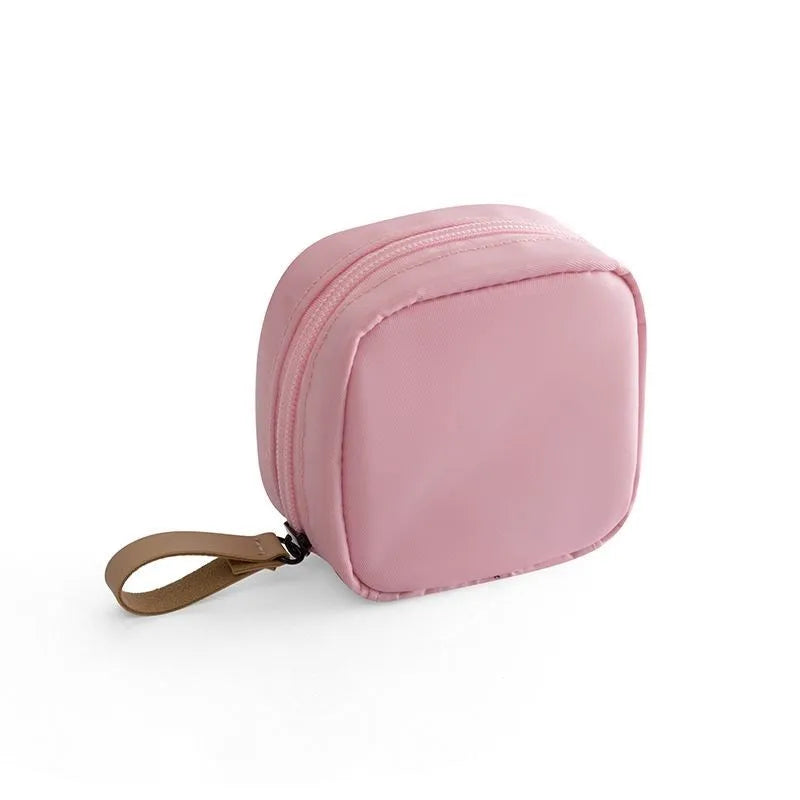 Blue cloth cube-shaped makeup bag with a zipper closure, resting on a surface.