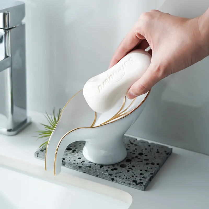 Ceramic leaf shape soap dish with hollow draining base and suction cup, black colour, on bathroom tiles