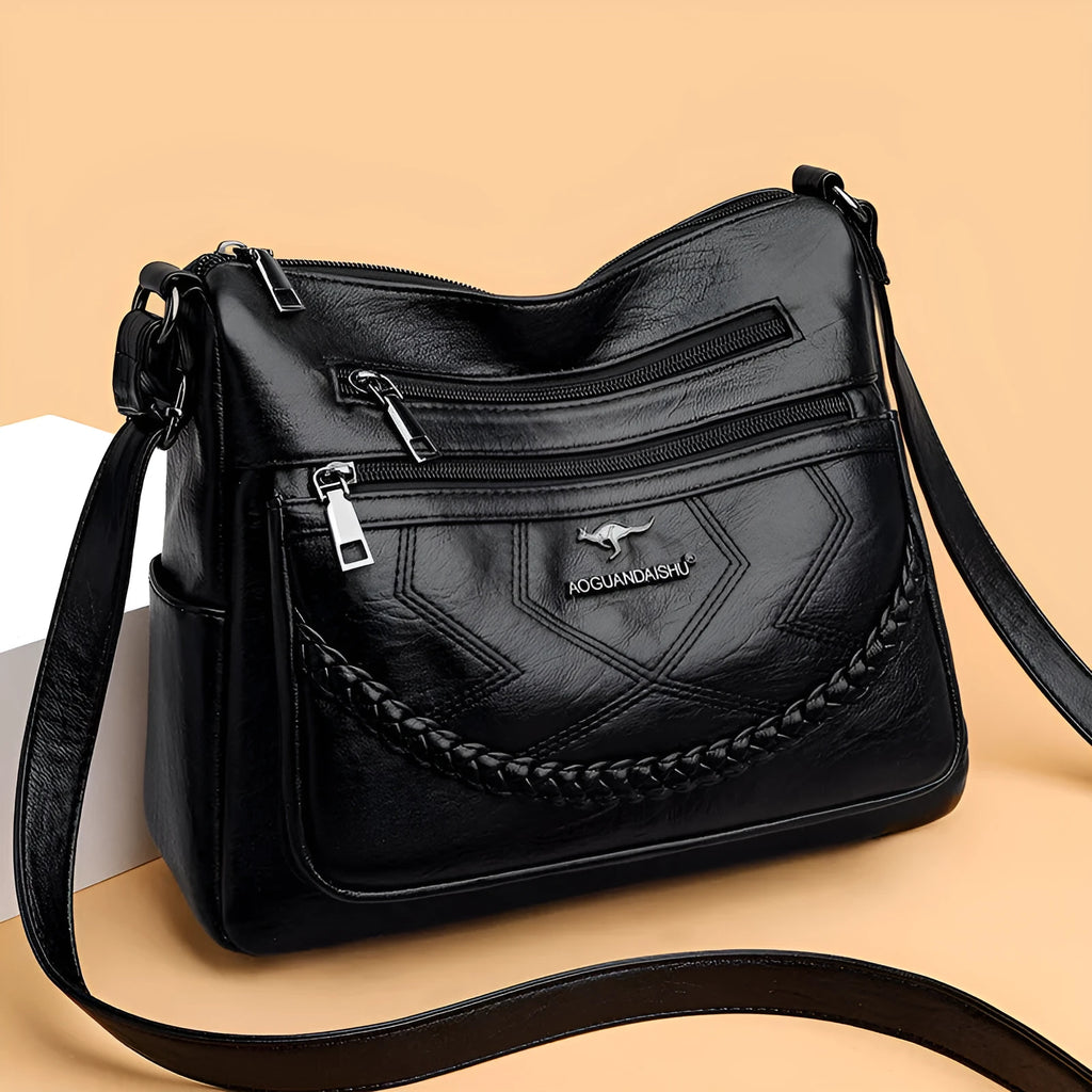 Soft PU leather women's shoulder bag in black colour showing crossbody strap and exterior pockets