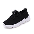Women's white fly knit slip-on sport shoes with a thick rubber sole and front strap.