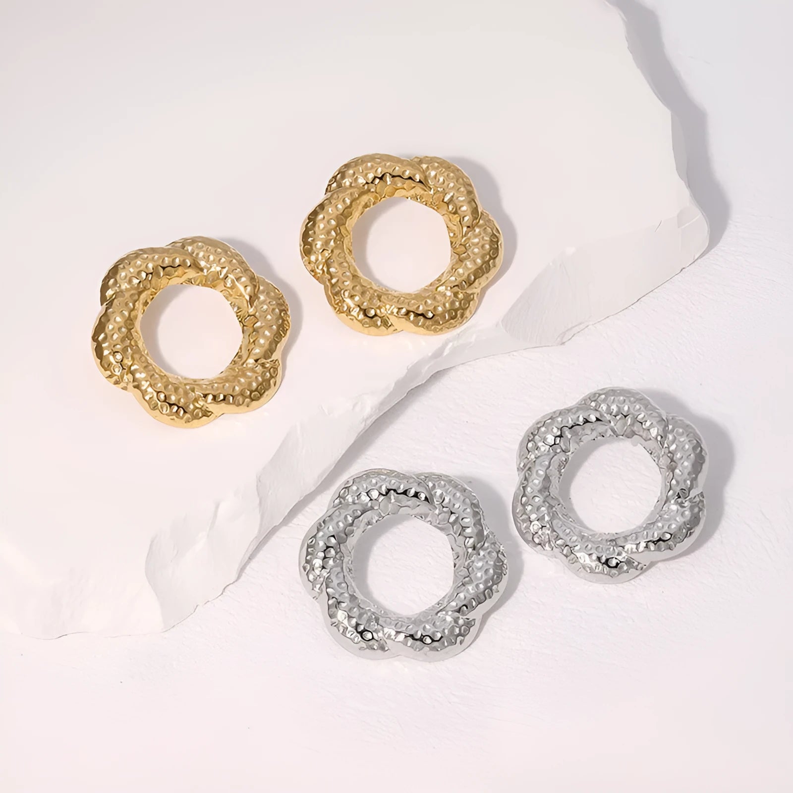 Stainless steel round stud earrings in gold and steel colours on a neutral background