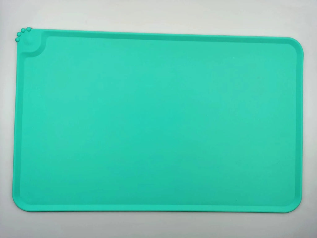 Silicone pet placemat under dog food and water bowls in a grey colour on a wooden floor.