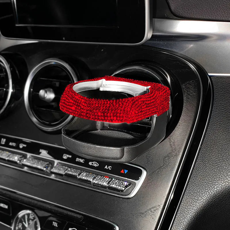 White diamond rhinestone car air vent cup holder bracket on a grey car dashboard.