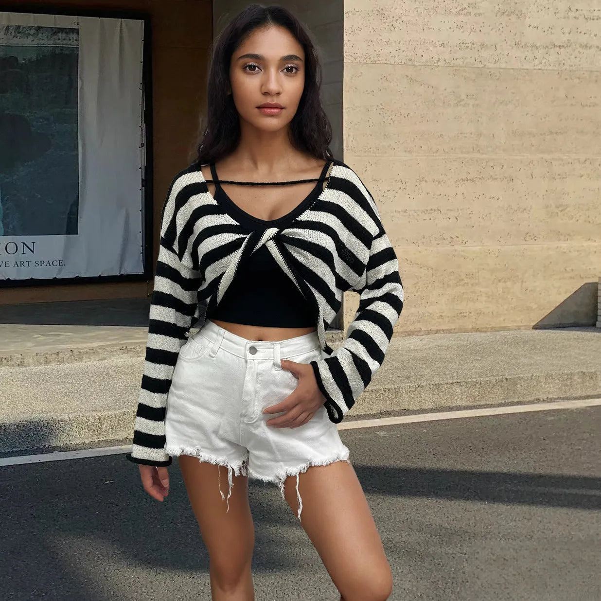 Woman wearing a striped long-sleeved sweater with an exposed navel, showcasing front and back wearable design in mercerised cotton.