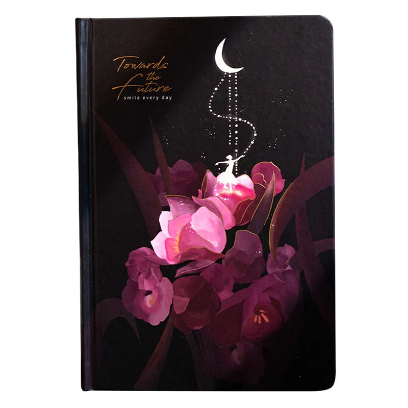 A5 notebook with luminous illustrated cover in blue, shown open on a desk.