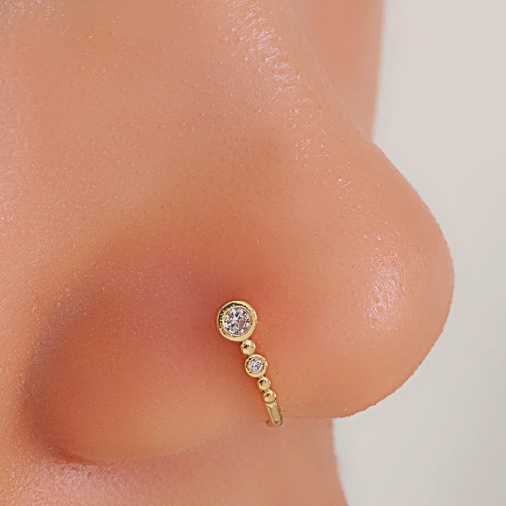 Copper U-shaped nose ring with zircon micro inlay, white K electroplated finish, shown on a flat surface