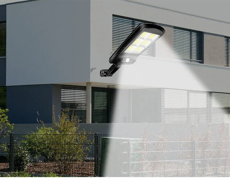 Black outdoor solar motion sensor wall light mounted on fence with LED illumination