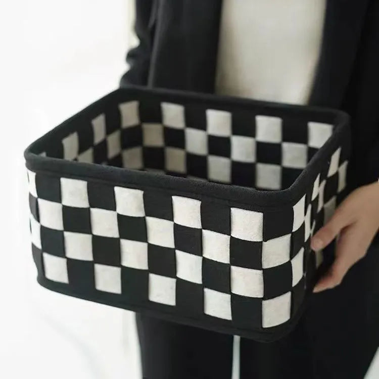 Checkerboard patterned grey felt storage basket with folded sides, shown empty.