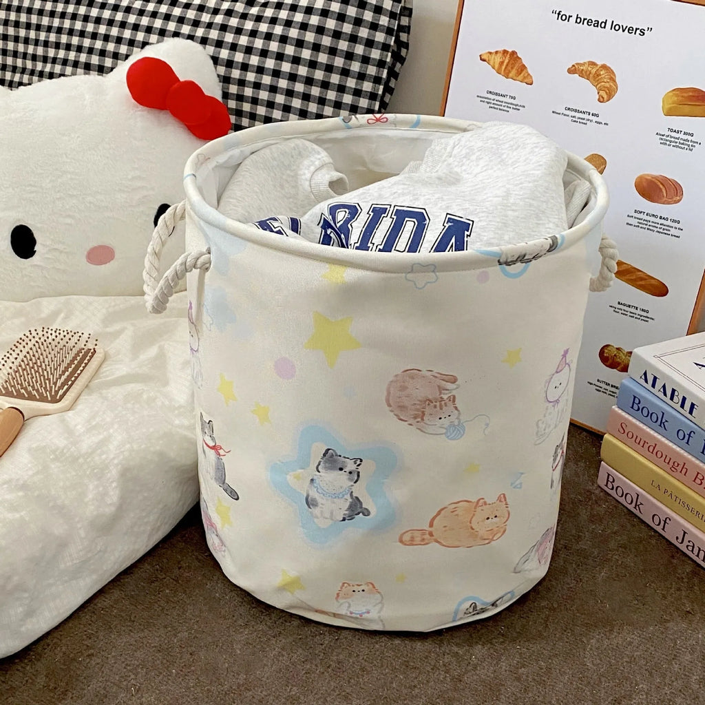 Foldable cotton laundry basket featuring an illustrated design, shown in a bedroom setting.