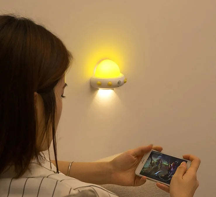 Remote control UFO shaped bedside night light in blue, pink or white colours on a table