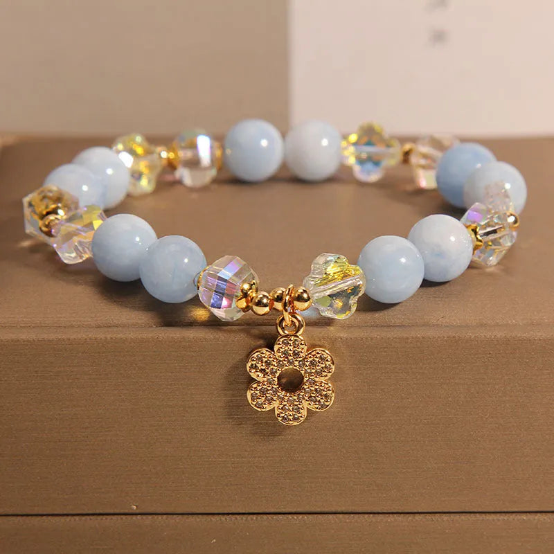 Women's aquamarine crystal bracelet with four-leaf clover charm and pearl accent on a chain