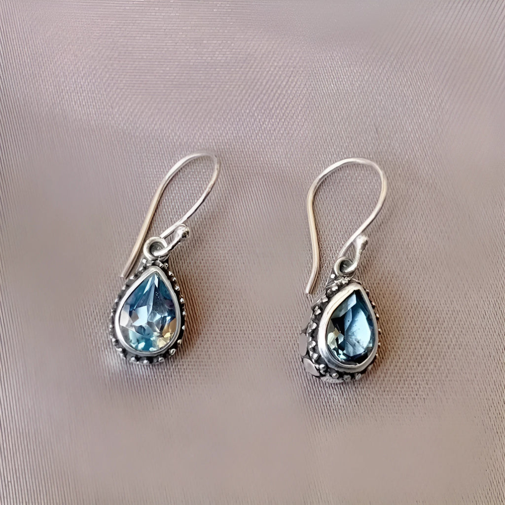 Pair of retro drop-shaped silver alloy earrings with blue gem inlay on white background