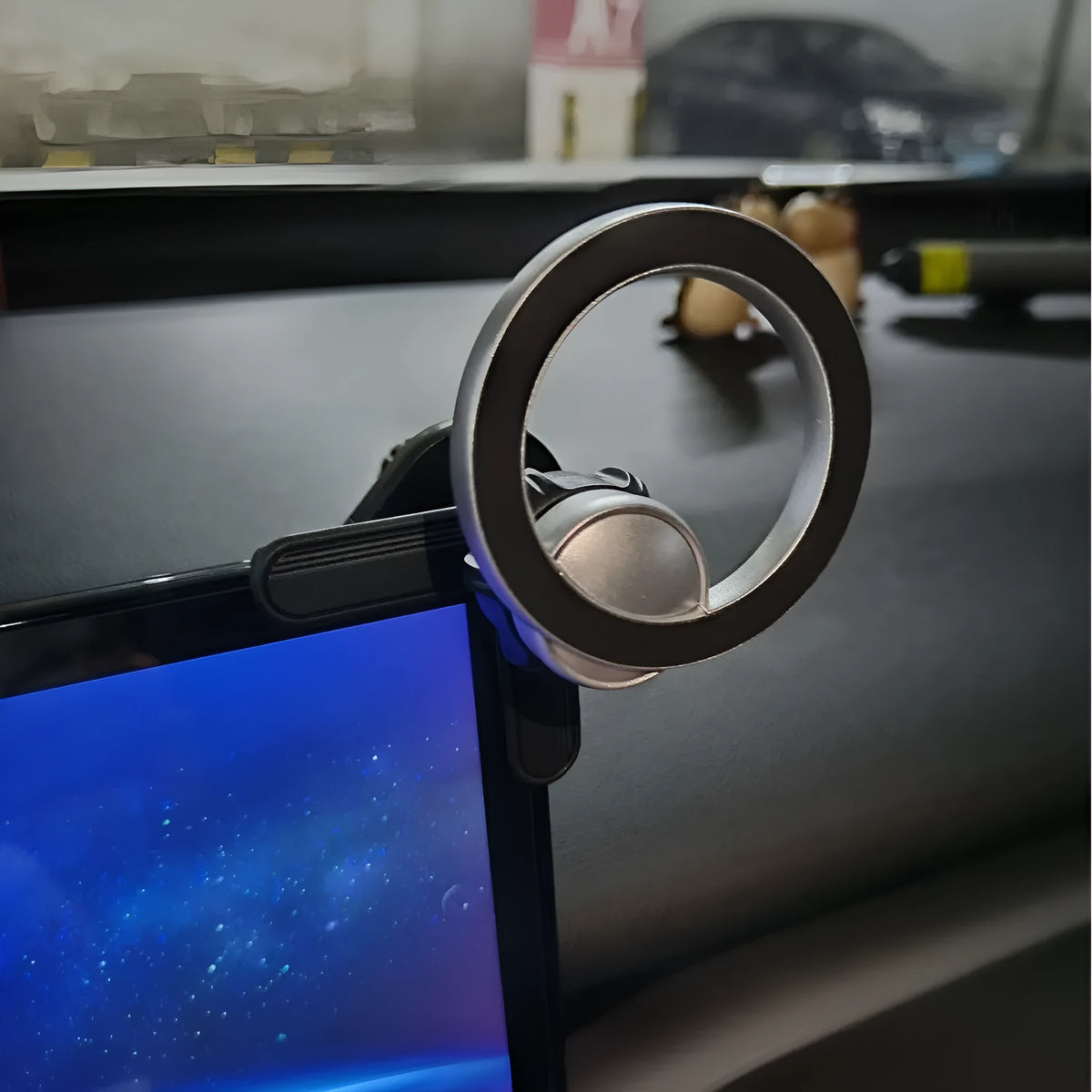 Black plastic magnetic ring phone holder attached to vehicle display screen with universal base and ring magnet