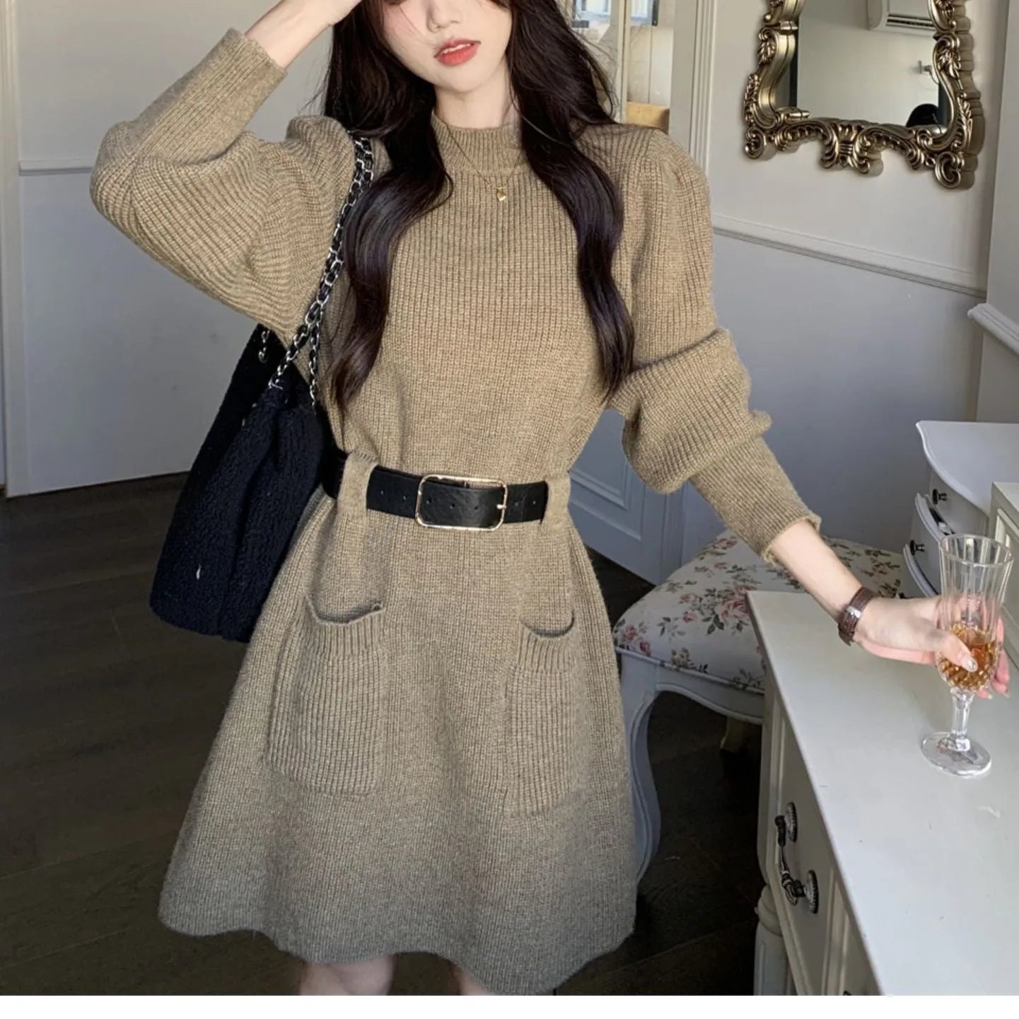 Long sleeve high-waist knitted dress on a hanger with a black belt, shown in beige colour.
