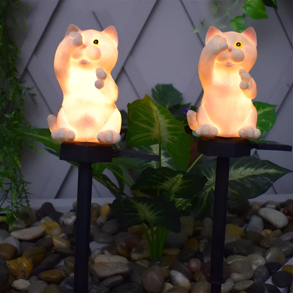 Brown cat-shaped solar lawn light in garden setting with LED illumination at dusk
