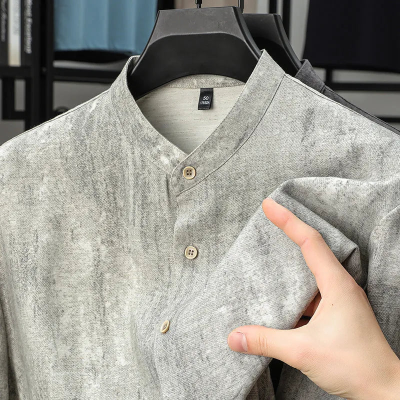 Man wearing a loose grey short sleeve cardigan shirt with a stand collar.