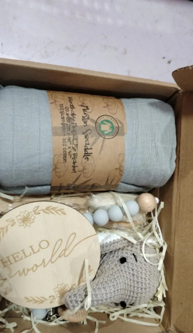 Baby teething toy gift set with bamboo blend gauze blanket, wooden beech bell, teether, brush, and milestone marker.