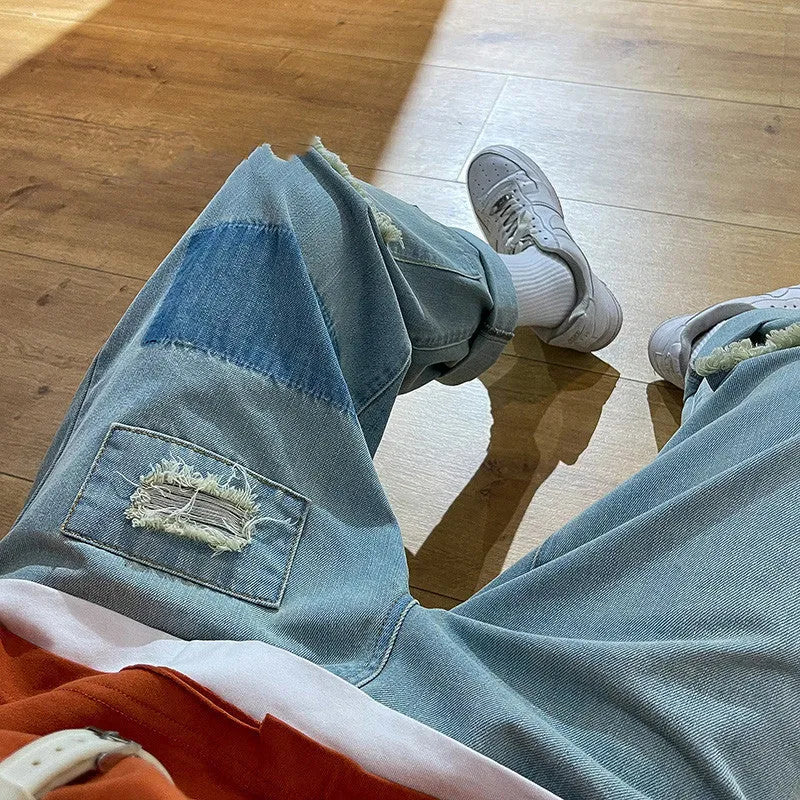 Men's high street ripped jeans with loose straight leg fit in black, showing rips on front thigh area